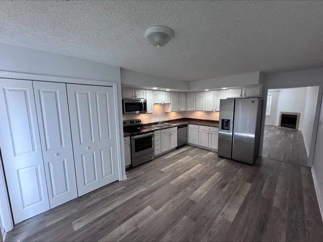 a kitchen with stainless steel appliances a refrigerator and wooden floor