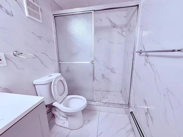 a white toilet sitting next to a shower