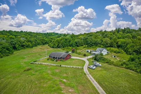 an aerial view of a residential houses with outdoor space and trees