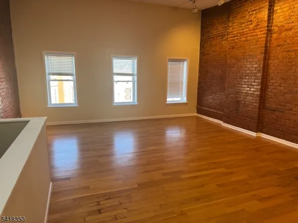 a view of an empty room with glass door and wooden floor