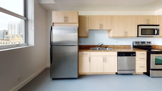 a kitchen with stainless steel appliances a refrigerator a stove a sink and white cabinets