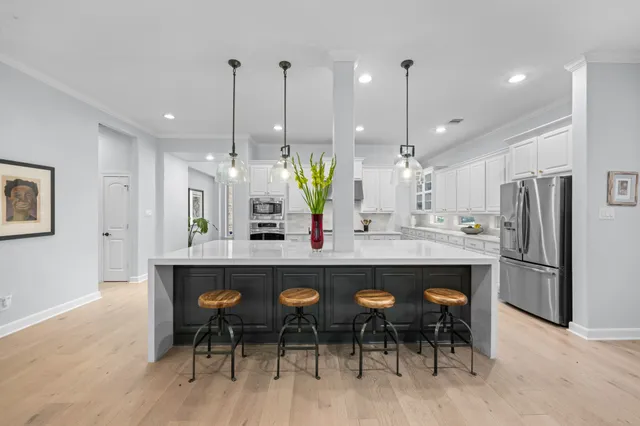 a kitchen with stainless steel appliances kitchen island granite countertop a dining table chairs and white cabinets