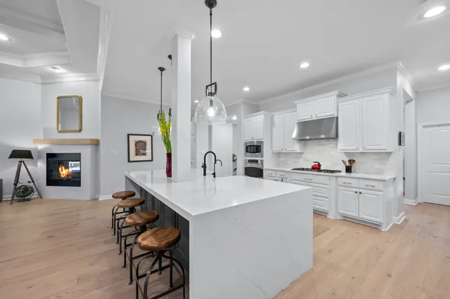 a large white kitchen with a sink a stove a dining table and chairs