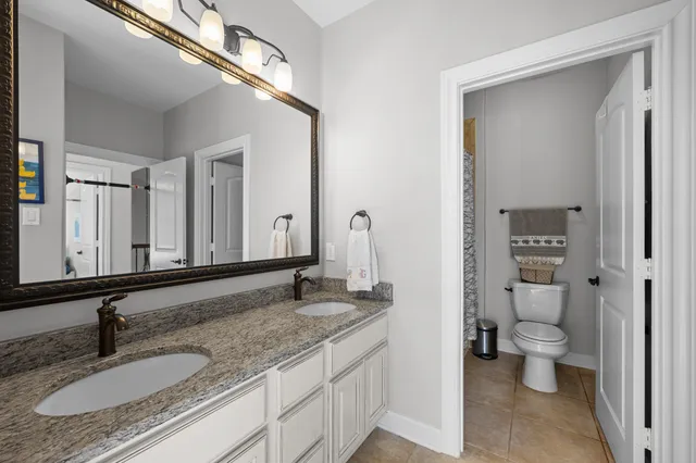 a bathroom with a granite countertop sink a toilet and a large mirror