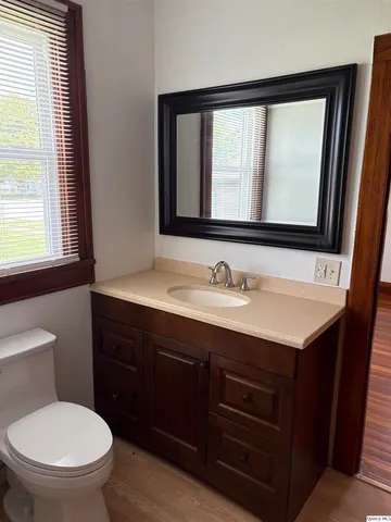 a bathroom with a toilet sink vanity mirror and window