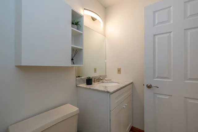a bathroom with a granite countertop sink toilet and mirror