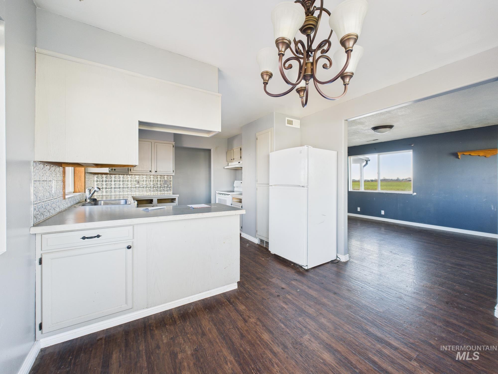 7352 Custer Road Fruitland, ID 83619 - Photo 11 of 43 Kitchen with white appliances, light countertops, a peninsula, a chandelier, and dark wood finished floors