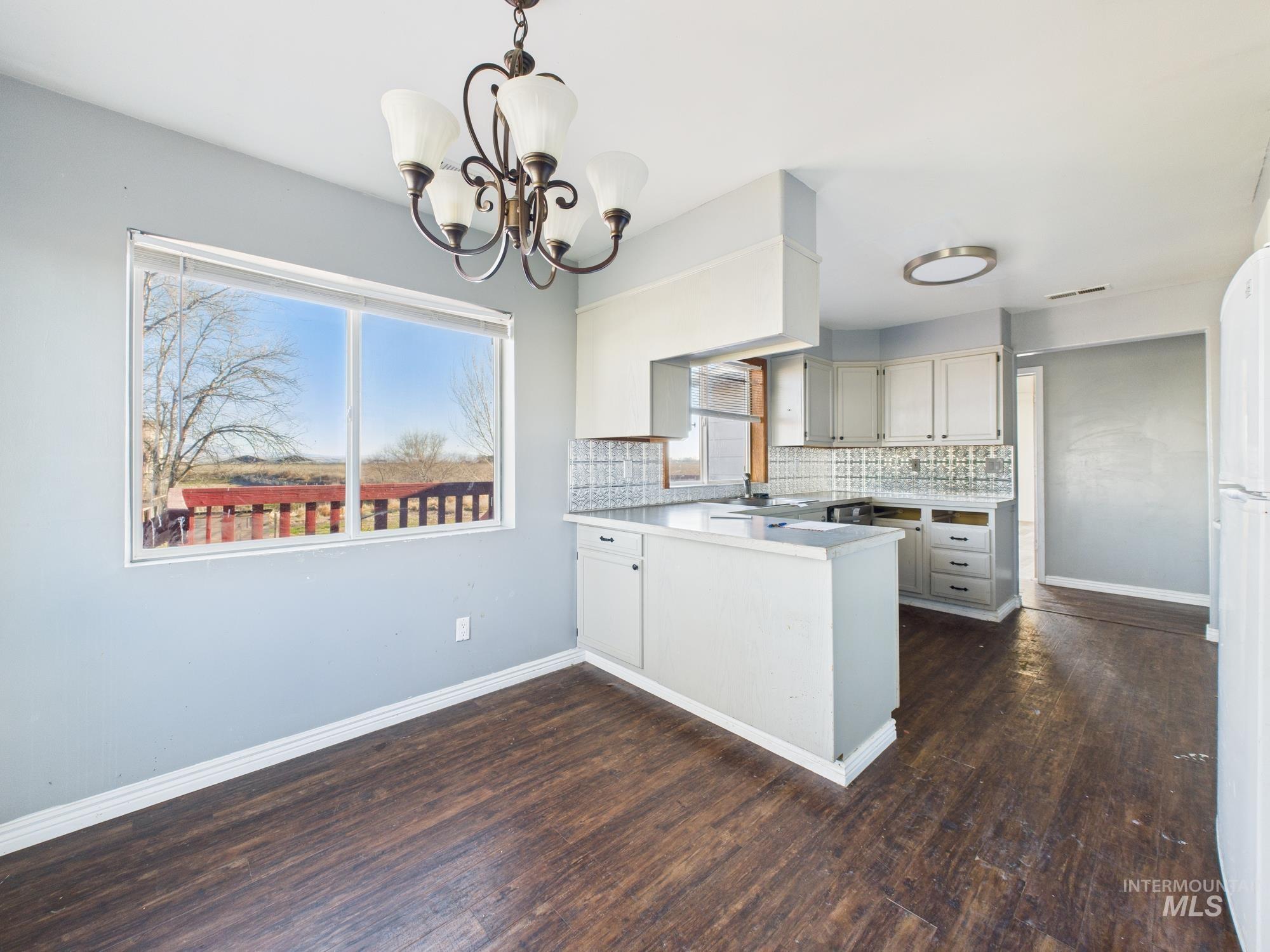 7352 Custer Road Fruitland, ID 83619 - Photo 12 of 43 Kitchen with light countertops, a peninsula, backsplash, pendant lighting, and a chandelier