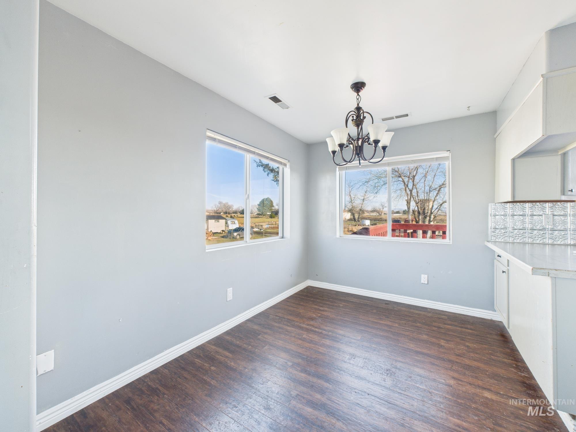 7352 Custer Road Fruitland, ID 83619 - Photo 13 of 43 Unfurnished dining area featuring dark wood-type flooring and a chandelier