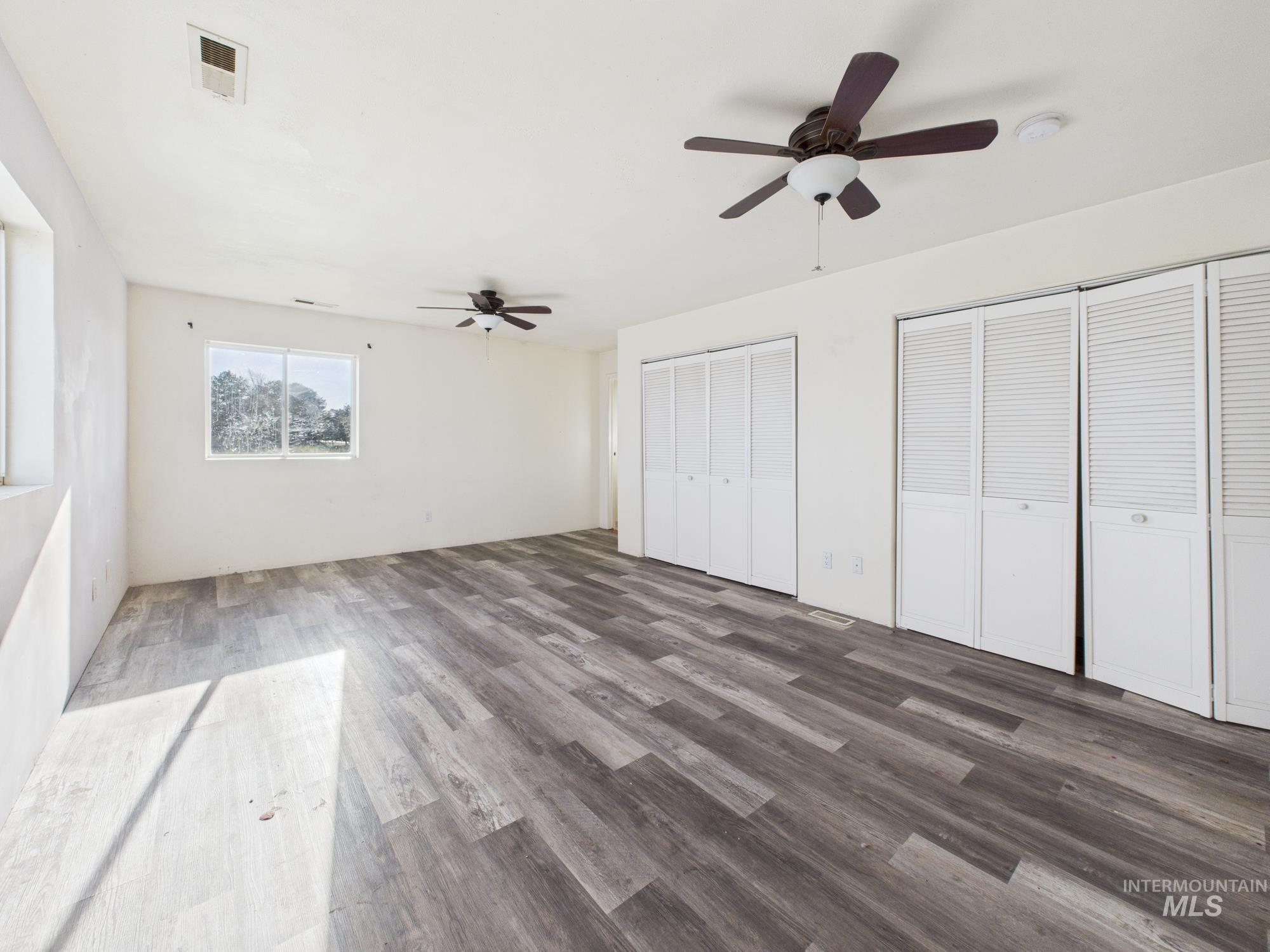 7352 Custer Road Fruitland, ID 83619 - Photo 14 of 43 Unfurnished bedroom featuring two closets, wood finished floors, and a ceiling fan