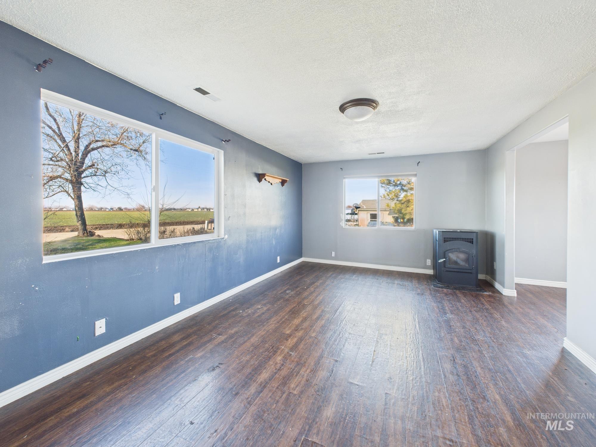 7352 Custer Road Fruitland, ID 83619 - Photo 4 of 43 Unfurnished living room featuring a wood stove, a textured ceiling, and dark wood-style flooring