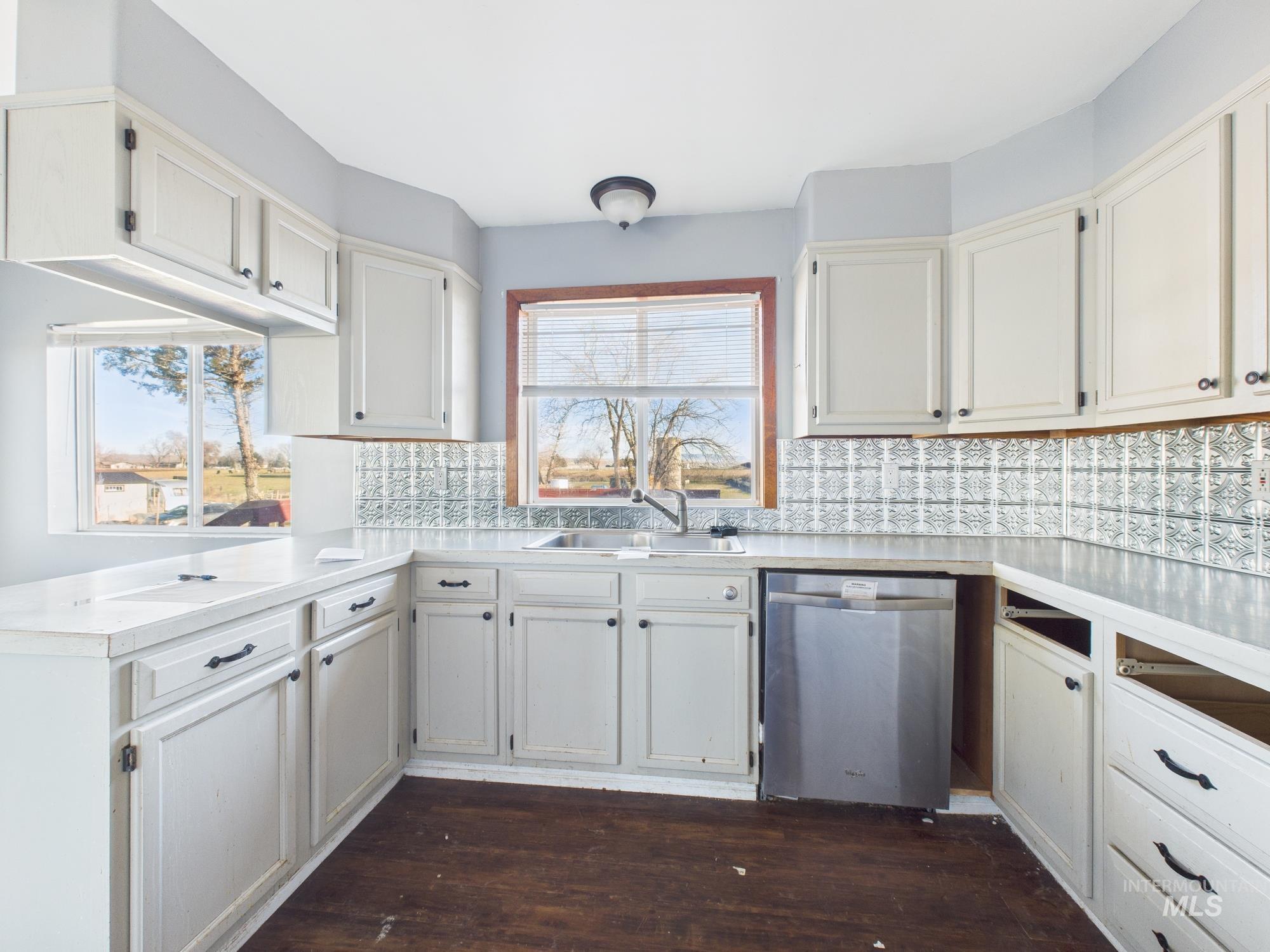 7352 Custer Road Fruitland, ID 83619 - Photo 6 of 43 Kitchen with dishwasher, light countertops, dark wood-type flooring, decorative backsplash, and white cabinetry