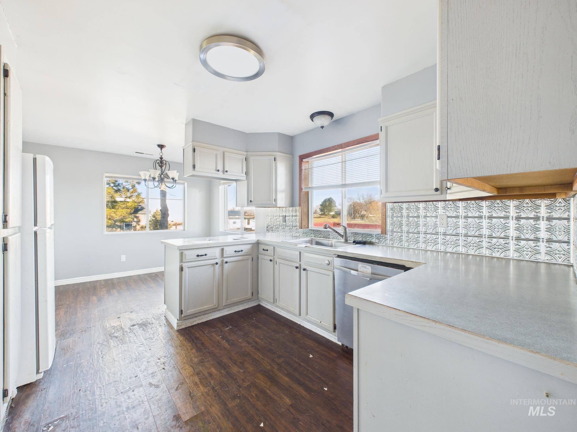 7352 Custer Road Fruitland, ID 83619 - Photo 7 of 43 Kitchen featuring a peninsula, dark wood-type flooring, light countertops, dishwasher, and backsplash