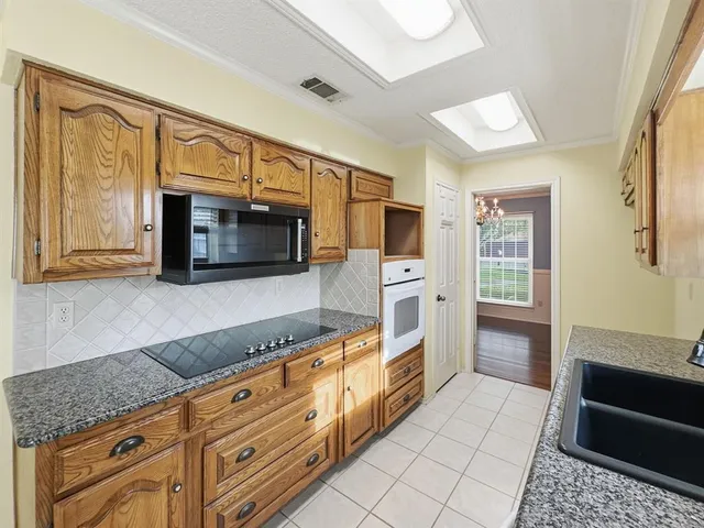 a kitchen with granite countertop a stove microwave and sink
