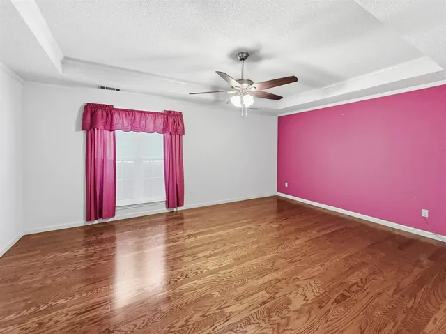 a view of empty room with wooden floor and fan