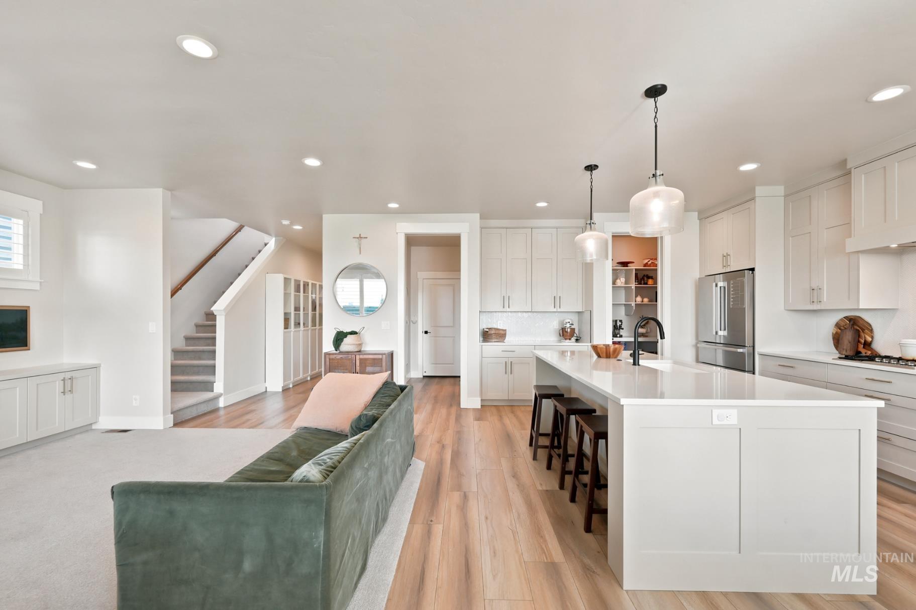 6933 South Zenith Avenue Meridian, ID 83642 - Photo 7 of 34 Spacious kitchen and living area featuring a large center island, extensive white cabinetry, wood-finish flooring, recessed lighting, and a carpeted living space