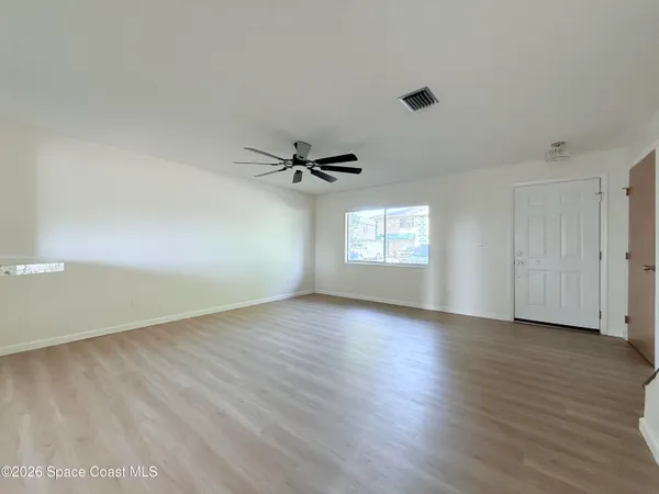 a view of an empty room with a window and wooden floor
