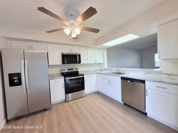 a kitchen with granite countertop stainless steel appliances a refrigerator cabinets and microwave