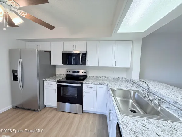 a kitchen with granite countertop a sink wooden floor and stainless steel appliances