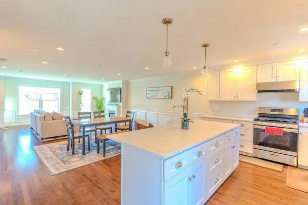 a large kitchen with stainless steel appliances granite countertop a stove and a wooden floors