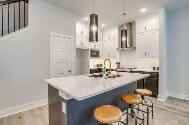 a kitchen with a sink a stove and chairs with wooden floor