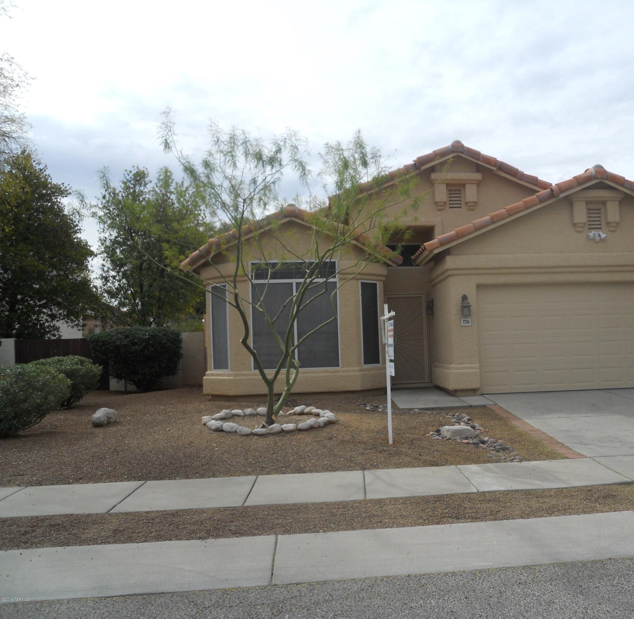 7736 East Elk Creek Road Tucson, AZ 85750 - Photo 1 of 11 a front view of a house with a garden