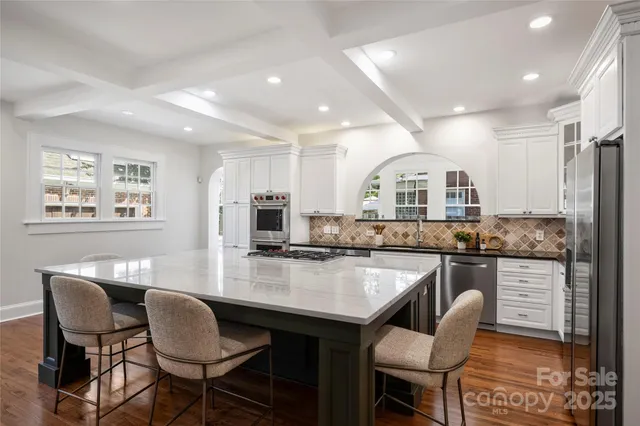 a kitchen with granite countertop a table chairs stove and refrigerator