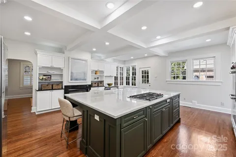 a kitchen with stainless steel appliances granite countertop a table chairs sink and white cabinets