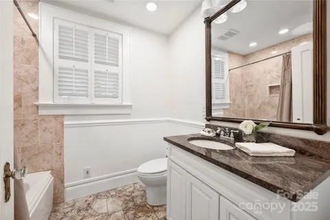 a bathroom with a granite countertop sink a toilet and a mirror