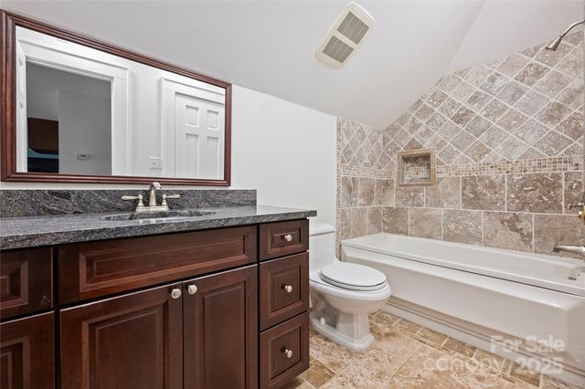 a bathroom with a granite countertop toilet a sink and a mirror
