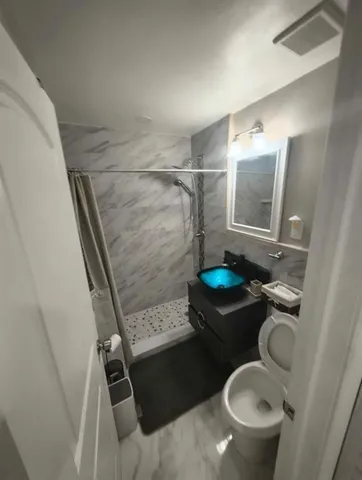 a bathroom with a granite countertop toilet and a shower