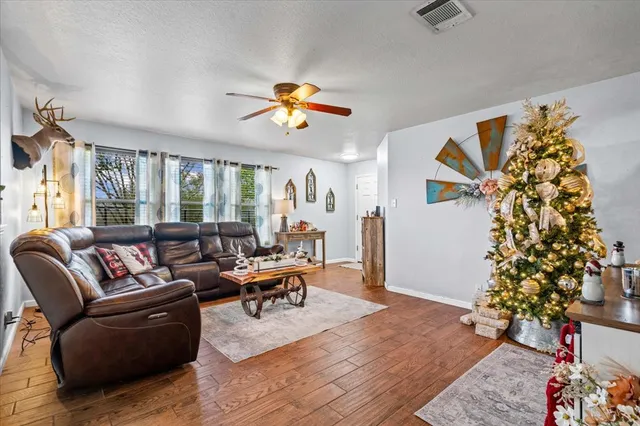 a living room with furniture kitchen view and a wooden floor
