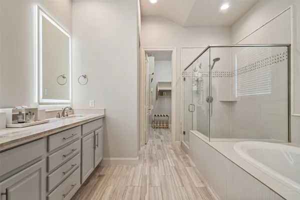 a bathroom with a tub sink vanity granite and shower