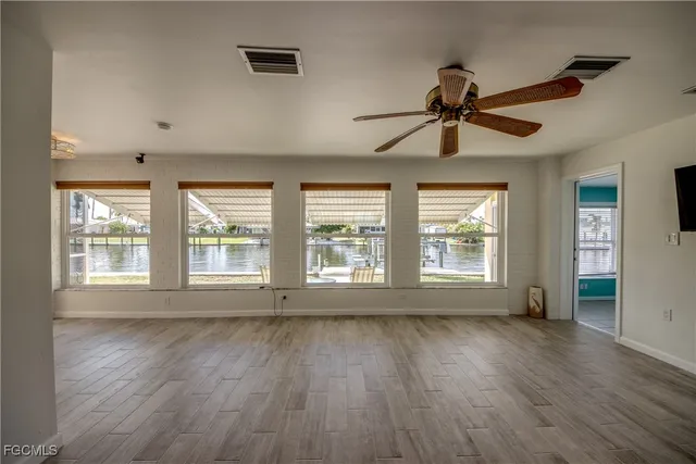 a view of an empty room with a window and wooden floor