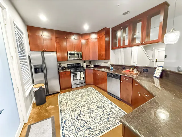 a kitchen with stainless steel appliances granite countertop sink stove refrigerator and cabinets
