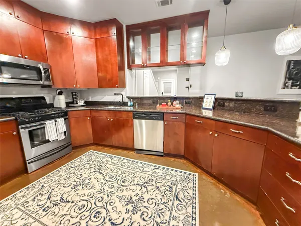 a kitchen with stainless steel appliances granite countertop a stove a sink and a microwave