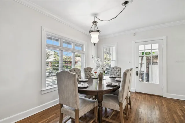a dining room with wooden floor a chandelier a wooden table and chairs