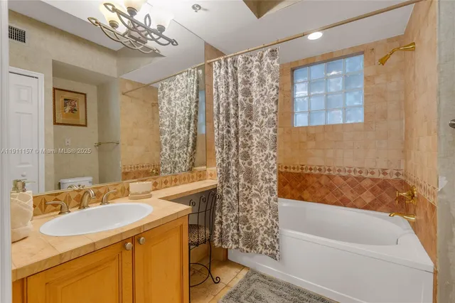 a bathroom with a sink a toilet a mirror a bathtub and shower