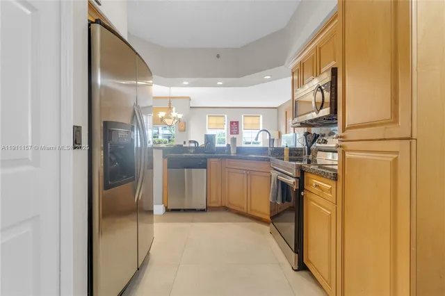 a kitchen with stainless steel appliances granite countertop a refrigerator a sink dishwasher and white cabinets with wooden floor