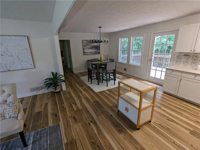 a dining room with wooden floor a chandelier a glass table and chairs