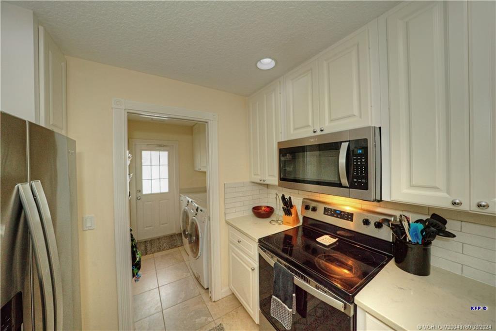 3073 East Community Drive Jupiter, FL 33458 - Photo 15 of 85 a kitchen with stainless steel appliances a stove a microwave and a refrigerator