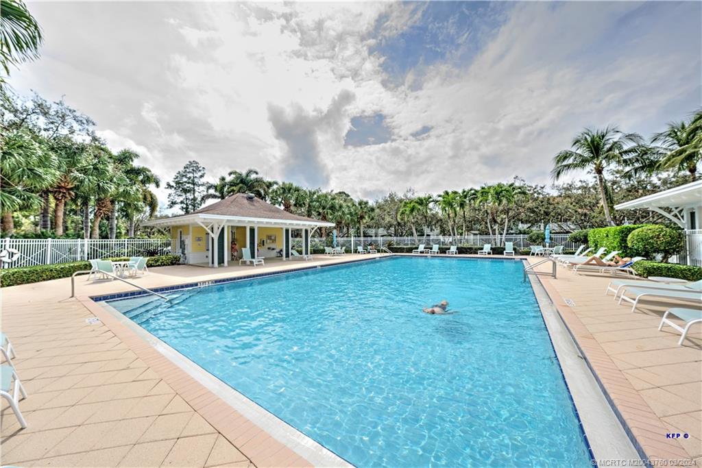 3073 East Community Drive Jupiter, FL 33458 - Photo 52 of 85 a view of a swimming pool with lawn chairs plants and large tree