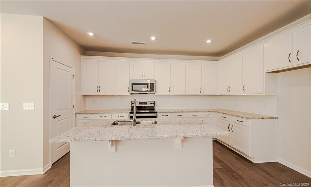 512 Madison Falls, Unit 6 Fort Mill, SC 29708 - Photo 6 of 27 a kitchen with kitchen island a sink a stove and white cabinets