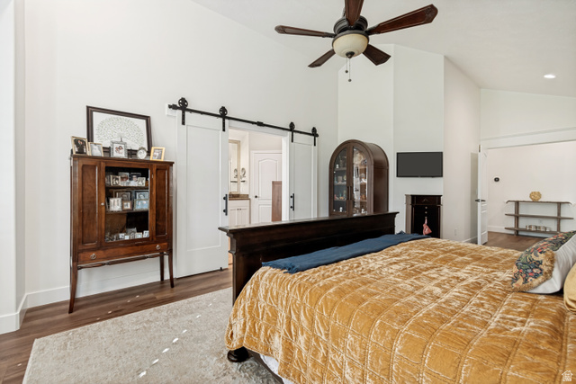 1567 Ridgeview Circle Farmington, UT 84025 - Photo 23 of 55 Spacious primary bedroom featuring hardwood flooring, a ceiling fan with dark wood blades, and a black metal barn-style sliding door leading to an ensuite area
