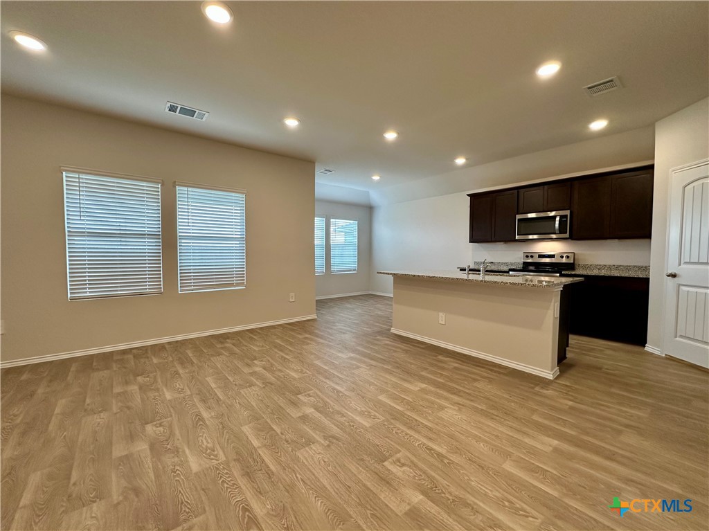 713 Signe Seguin, TX 78155 - Photo 2 of 18 a large kitchen with kitchen island a sink dishwasher a stove and a microwave oven with wooden floor