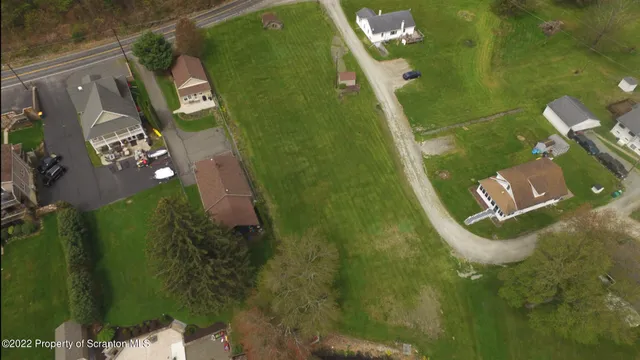 an aerial view of a residential houses with outdoor space and trees