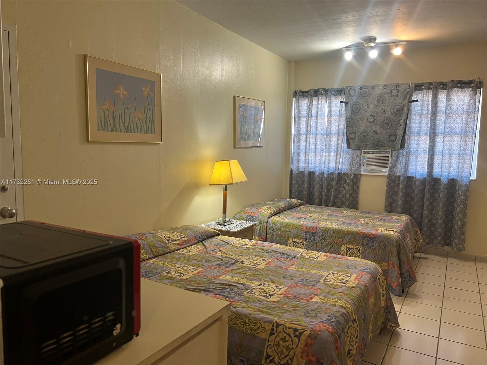 26 Diplomat Parkway, Unit 2332 Hallandale Beach, FL 33009 - Photo 2 of 18 a bedroom with a bed and a lamp