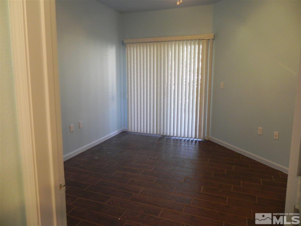 9050 Double R Boulevard, Unit 1112 Reno, NV 89521 - Photo 12 of 24 an empty room with wooden floor and windows with curtains
