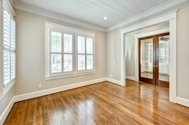 a view of an empty room with wooden floor and a window