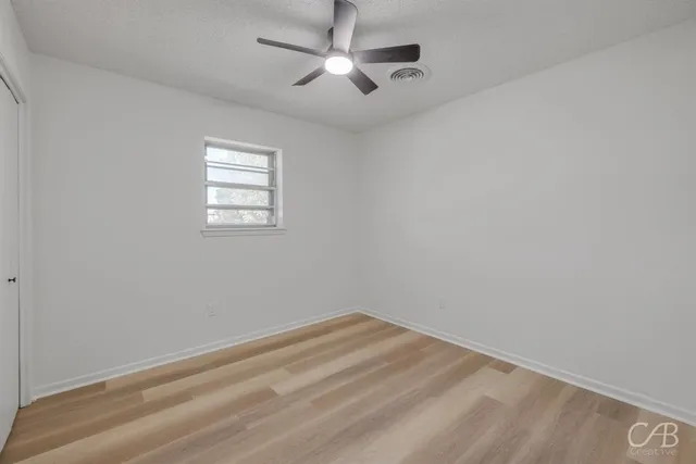 an empty room with a window and a fan